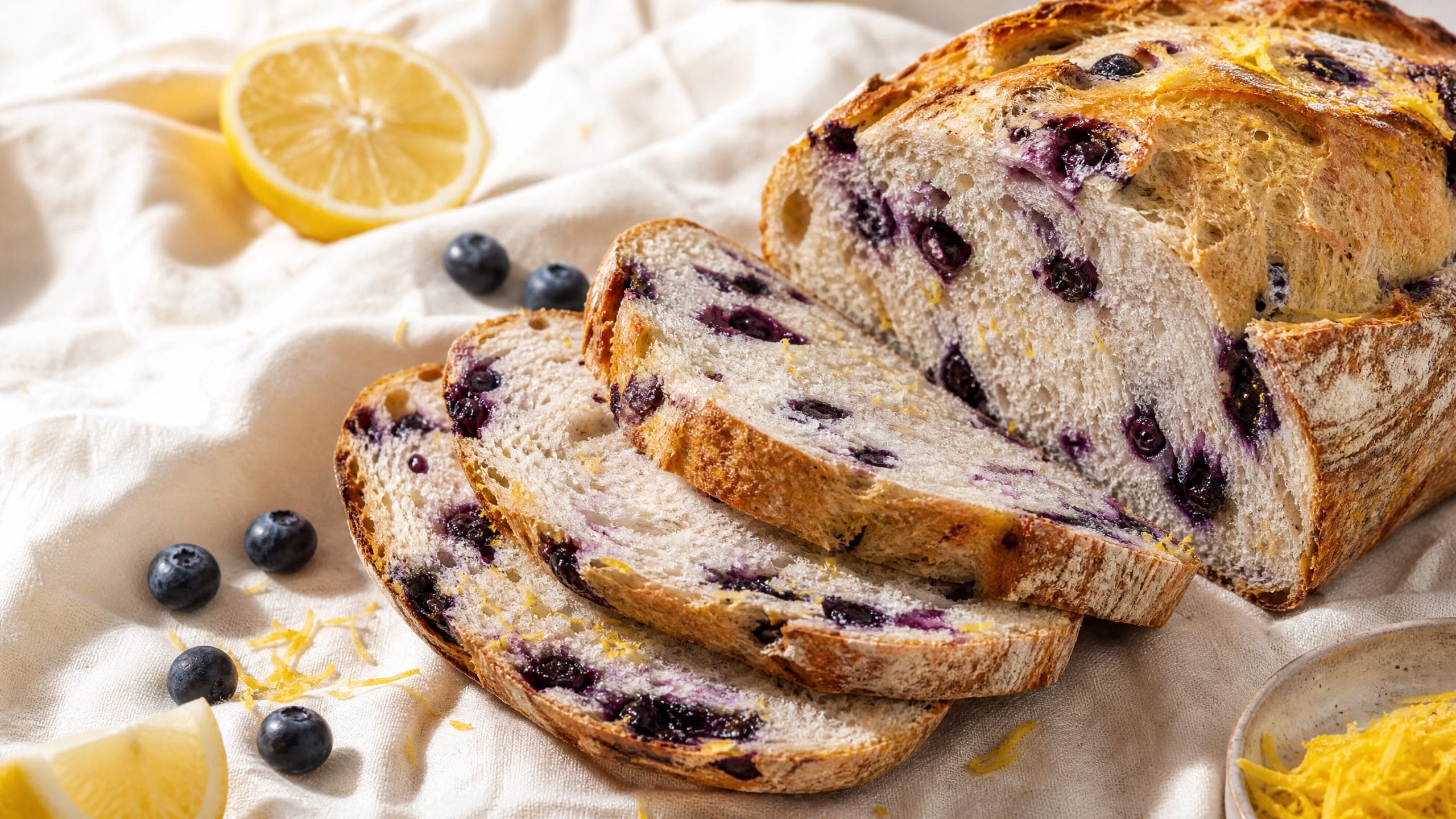 Freshly baked blueberry lemon sourdough bread, photographed on a warm cream background