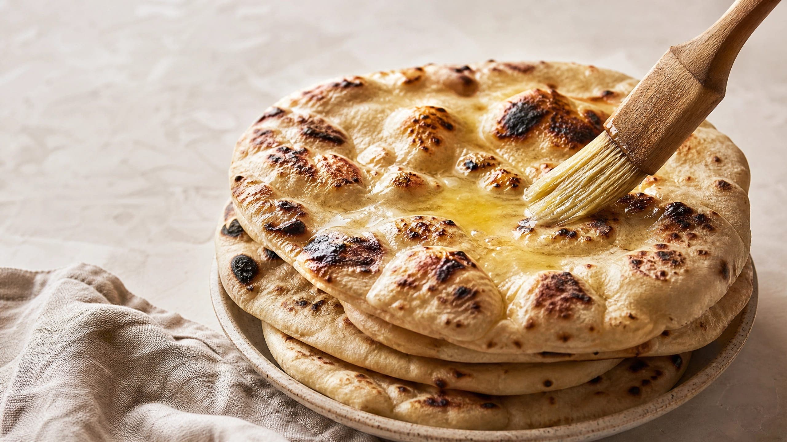 Freshly baked sourdough naan, photographed on a warm cream background