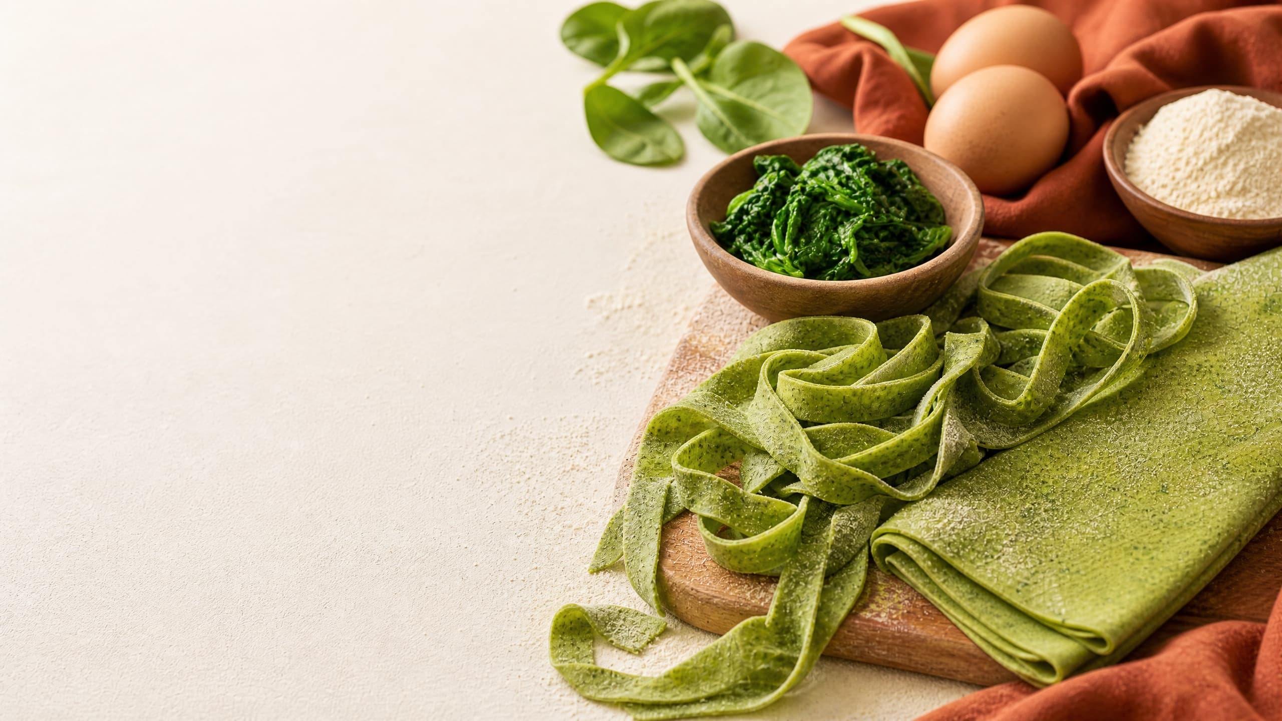 Freshly baked sourdough spinach pasta (bright fresh noodles), photographed on a warm cream background