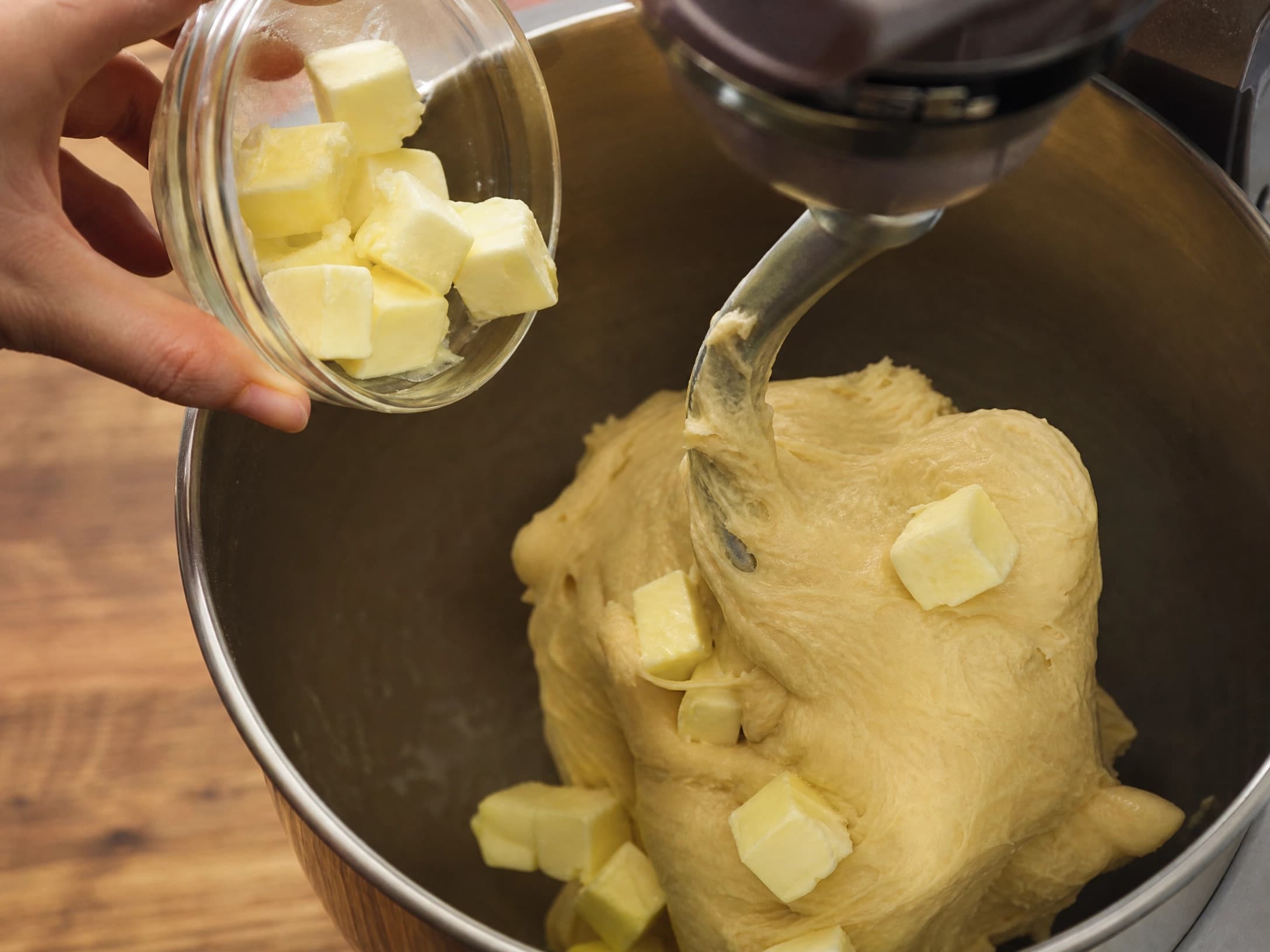 Softened butter being mixed into sourdough brioche dough